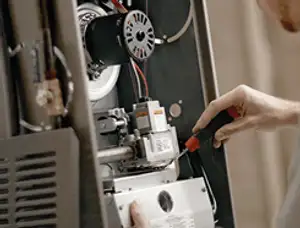 Furnace repair technician inspecting internal components and wiring in Lynchburg, VA