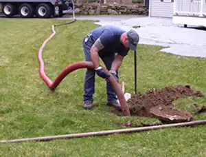 Septic pumping technician servicing a residential septic tank with a vacuum hose in Lynchburg, VA