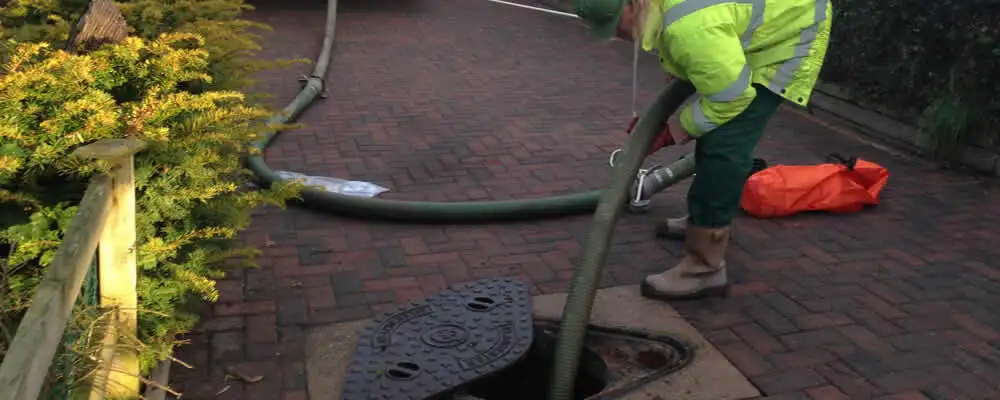 Septic tank cleaning technician servicing a septic tank with a vacuum hose in Lynchburg, VA