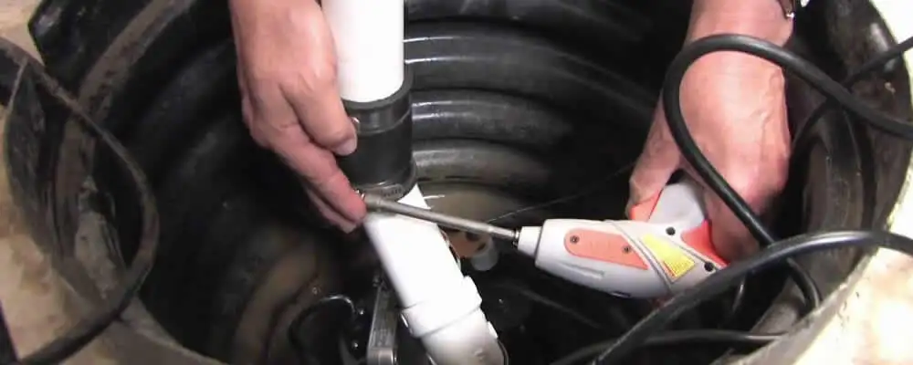 Sump pump installation technician connecting PVC discharge piping in Lynchburg, VA